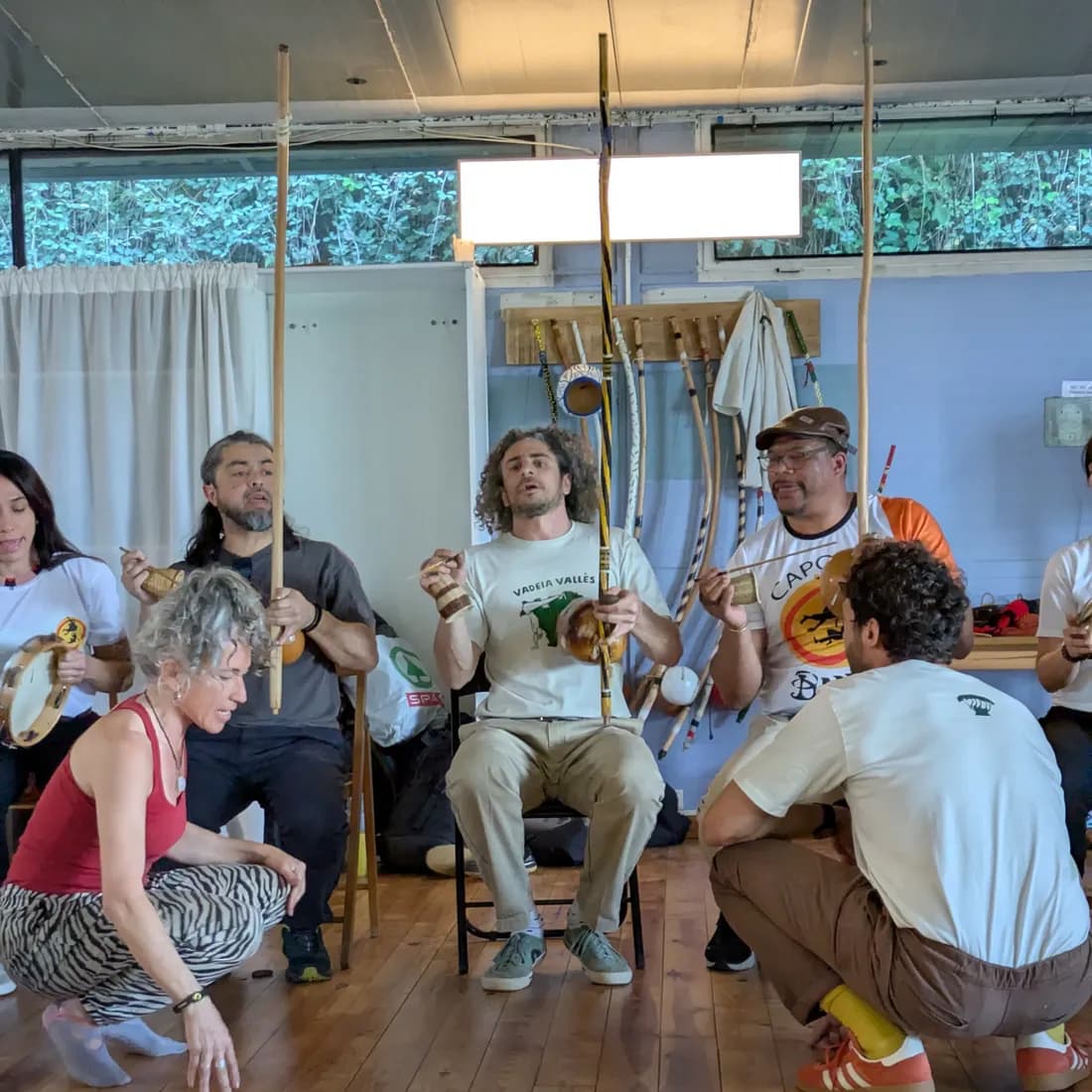 Cantant al peu del berimbau, amb dues persones a punt d’entrar a la roda.