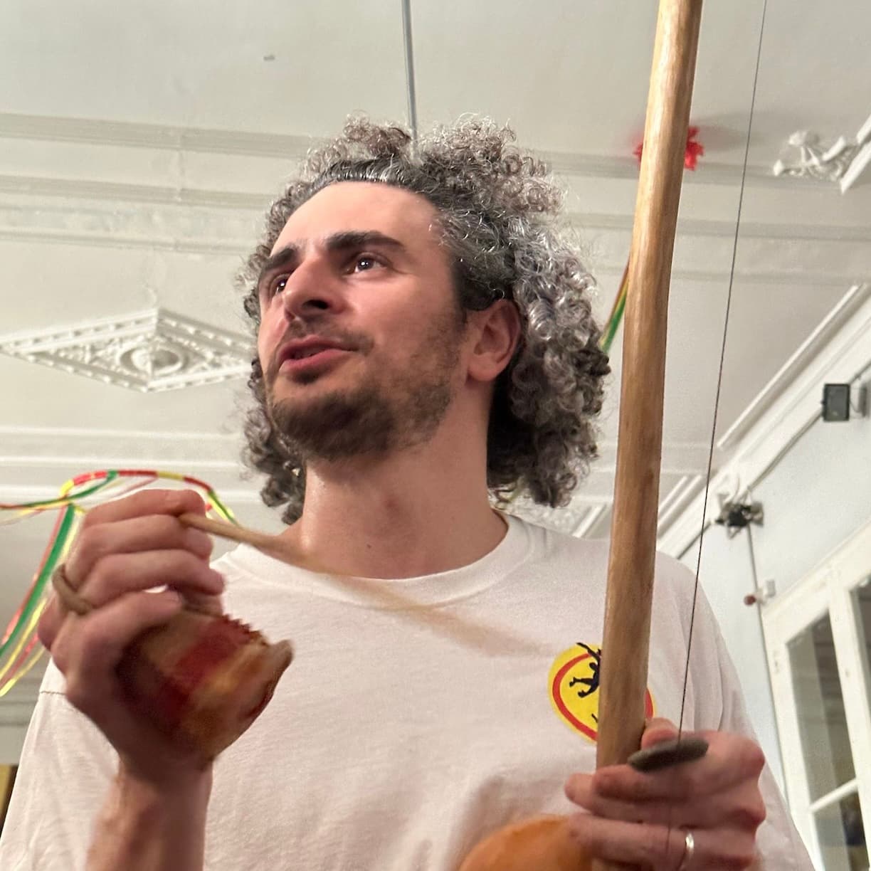 Tocant el berimbau i el caxixi, amb la samarreta del grup.